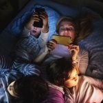 family praying beside a bed at night, asking God for peaceful sleep and protection.
