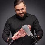 smiling butcher scratching meat with knife FD5WRHN